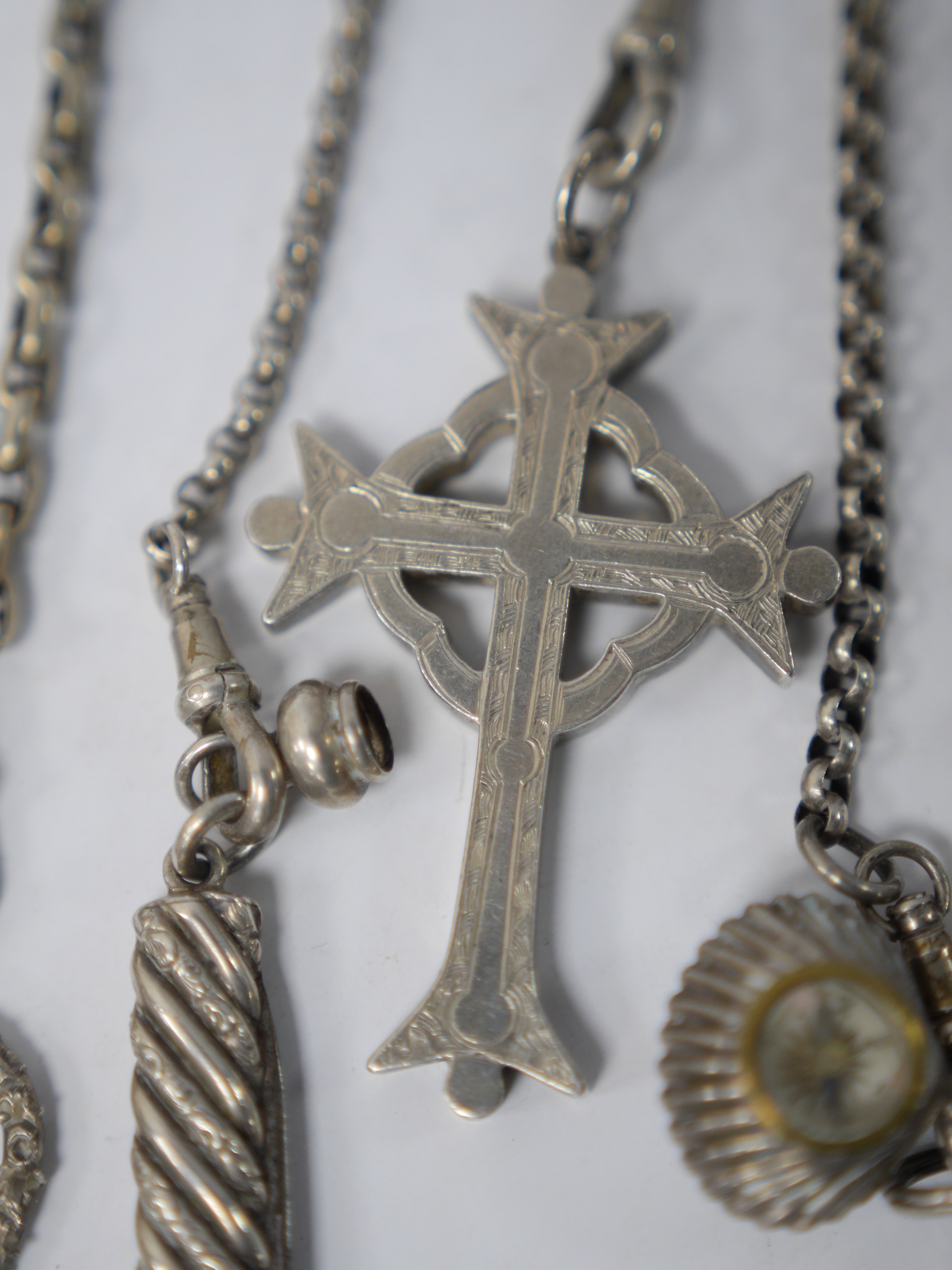 A late 19th/early 20th century continental white metal chatelaine, hung with six assorted accoutrements including a small silver box, a George III silver oval snuff box, a pen knife, compass and cross pendant. overall ap